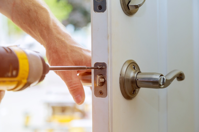 A man is drilling into a door, working on a home repair project in Vancouver, BC