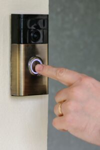 A man presses the button on a "Ring" internet video door-bell from ring.com.