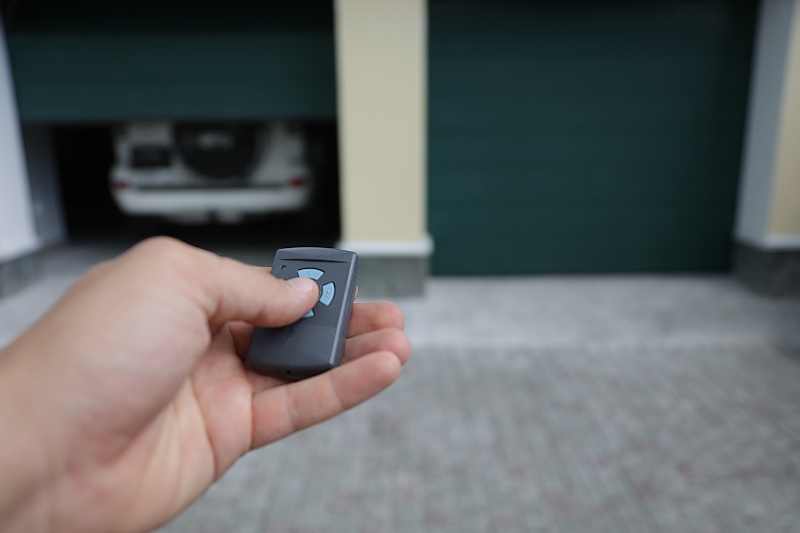 Person opens the garage door in which the car is located with a remote control in Vancouver, BC